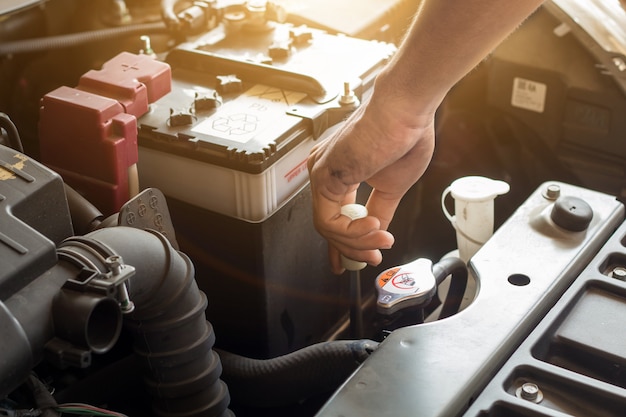 Auto-mechanik Pracuje Sprawdzając Wodę W Układzie I Napełnić Stary Silnik Samochodu Na Stacji Paliw, Wymienić I Naprawić Przed Jazdą