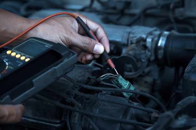 Auto mechanik przy użyciu urządzeń pomiarowych do sprawdzania elektrycznego samochodu.