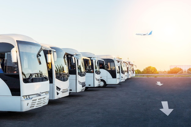 Autobusy na parkingu na lotnisku o wschodzie słońca. Letnia koncepcja podróży, turystyki i wakacji.