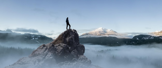 Awanturniczy turysta stojący na szczycie Rocky Peak Adventure Composite Sunny Sunrise Nature Background