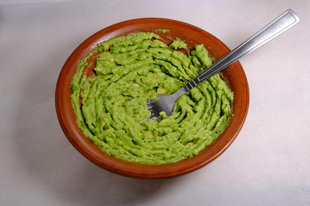 Awokado zmielone guacamole na meksykańskim molcajete na kolorowym tle Meksykańskie jedzenie