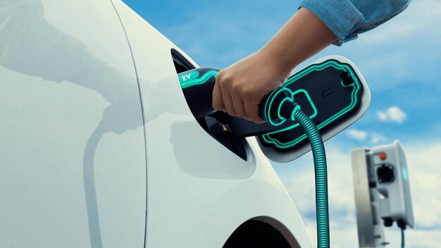 Zdjęcie azjat ładuje swój samochód elektryczny ładowarką elektryczną peruse