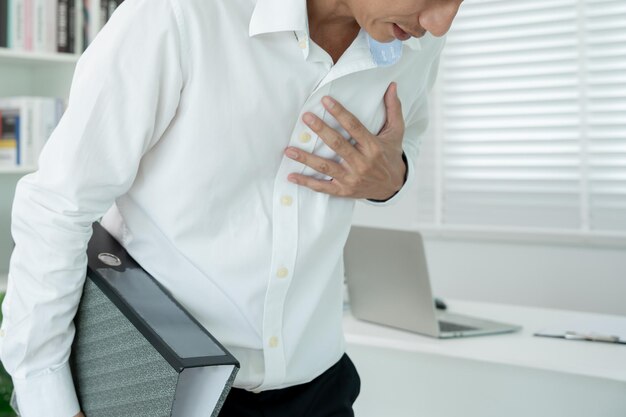 Azjat pracujący ciężko ma ból w klatce piersiowej spowodowany chorobą serca wyciek rozszerzenie powiększonej wieńcowej serca naciskaj na klatkę piersiową z bolesnym wyrazem twarzy