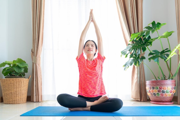 Zdjęcie azjatka ćwiczy w swoim salonie z matą do jogi w domu