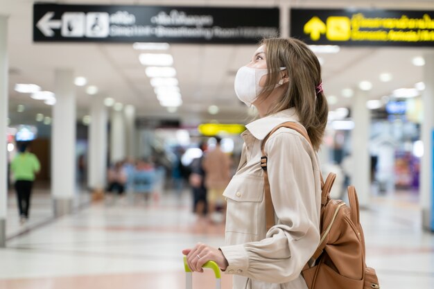 Azjatka nosi maski podczas podróży na terminalu lotniska Nowy normalny covid