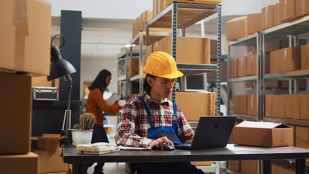 Azjatka planuje zarządzanie zamówieniami w magazynie, używając laptopa do inwentaryzacji zapasów. Pracownik płci męskiej pracujący z produktami w magazynie, łańcuchu dostaw i skrzynkach dystrybucyjnych.