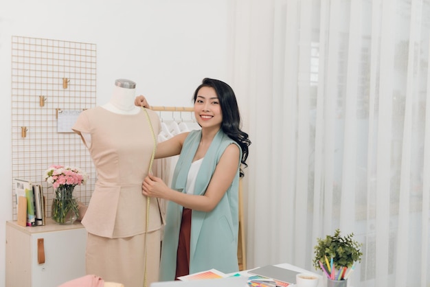 Azjatka pracuje w pracowni warsztatowej Dopasowuje sukienkę na manekinie