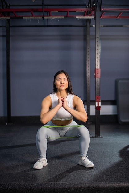 Azjatka robi ćwiczenia z gumką fitness na siłowni