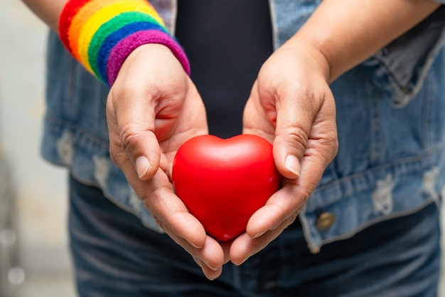 Azjatka Ubrana W Tęczowe Opaski Na Rękę I Trzymająca Czerwone Serce, Symbol Miesiąca Dumy Lgbt.