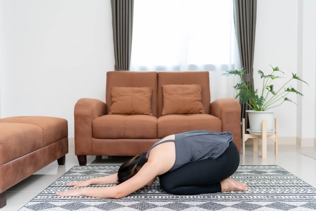 Azjatka uprawiająca jogę i rozciągająca się w salonie w domu Koncepcja ćwiczeń w celu stworzenia zdrowego ciała dla siebie
