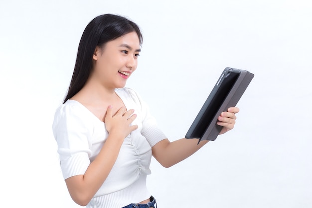 Azjatka w białej koszuli patrzy na tablet w dłoni podczas telekonferencji