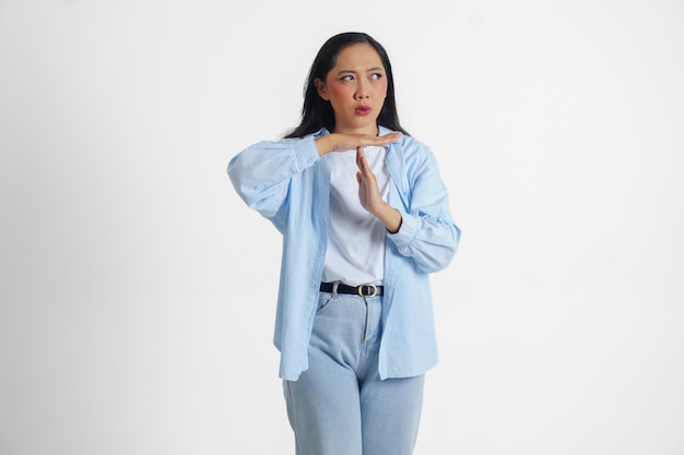 Azjatka w niebieskiej koszuli robiąca gest z rękami i poważną twarzą z izolowanym białym tłem