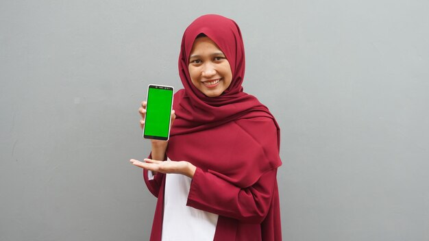 Azjatka wskazująca na telefon z zielonym ekranem