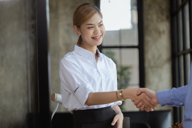 Azjatki ściskają ręce z partnerami biznesowymi młode i energiczne azjatyckie kobiety biznesu tworzące nowoczesną firmę zarządzającą startupem Koncepcja liderek prowadzących biznes