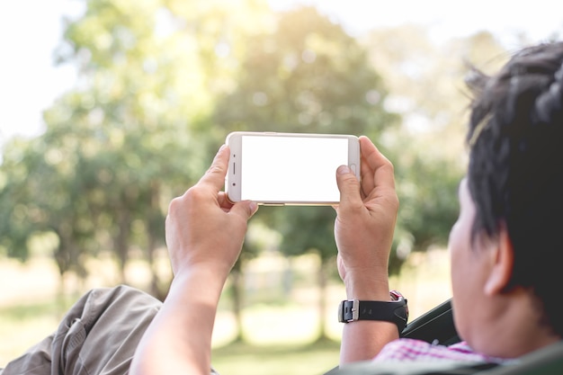 Azjatyccy mężczyzna używają smartphone w parku.