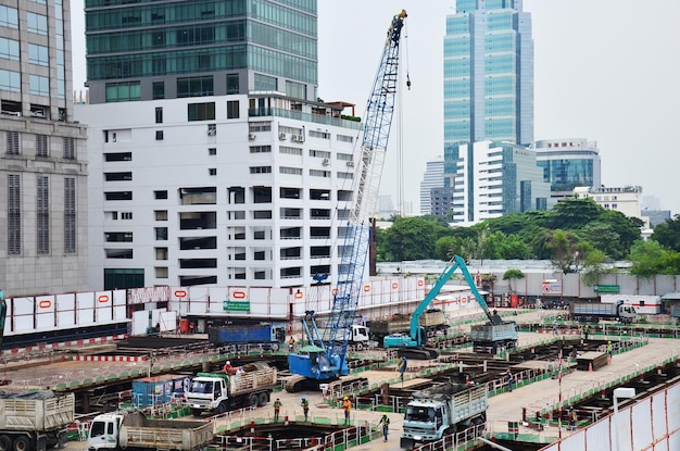 Azjatyccy robotnicy i tajscy pracownicy korzystają z maszyn i ciężkich maszyn pracujących budowniczym nowej budowy