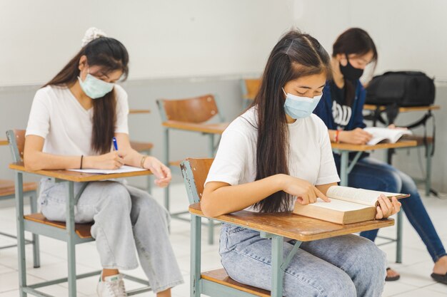 Azjatyccy Studenci Wracający Do Szkoły Noszą Maskę Na Twarz I Uczą Się Na Odległość W Klasie