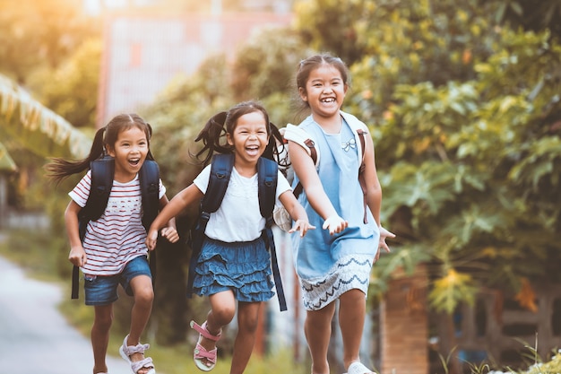 Azjatyccy uczni dzieciaki z plecakiem biega wpólnie i iść szkoła