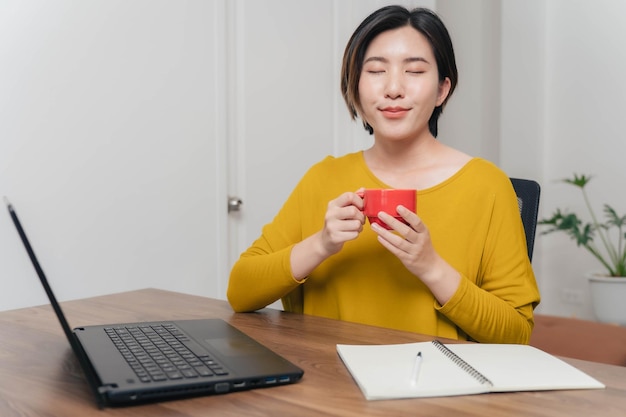 Azjatycka bizneswoman pijąca kawę, aby wyleczyć koncepcję senności Azjatycka kobieta dobrze się bawi pijąc kawę podczas pracy