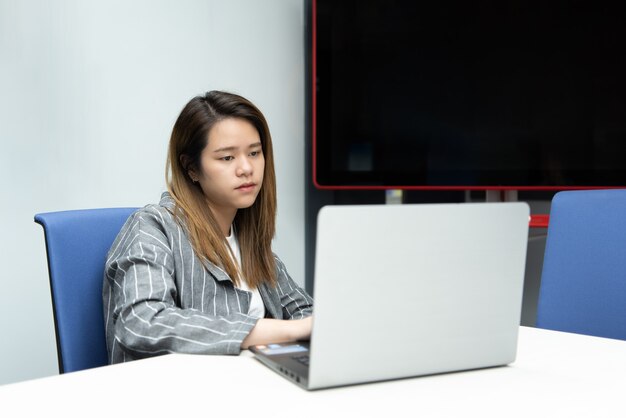 Azjatycka bizneswoman pracuje na laptopie w biurze z emocjami zirytowanych i niezadowolonych