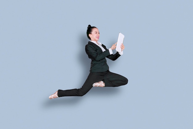 Azjatycka bizneswoman tańczy z tabletem w studiu