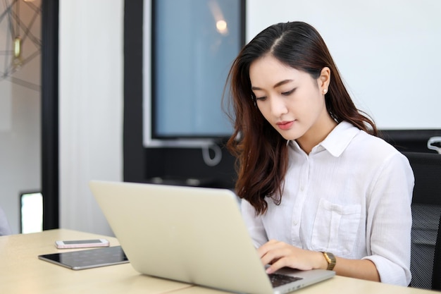 Azjatycka bizneswoman używa laptopa do pracy i robi badania internetowe w swoim biurze