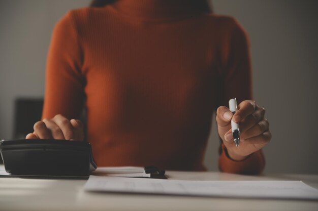 Azjatycka bizneswoman Używa laptopa i pracuje w biurze z dokumentem kalkulatora na biurku, planując analizując raport finansowy biznesplan koncepcja analizy finansów inwestycji
