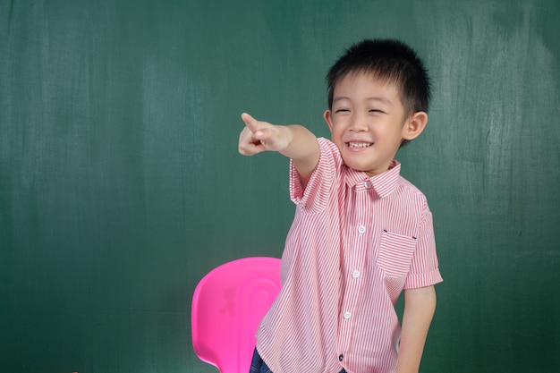 Azjatycka chłopiec wskazuje w kredowej deski pokoju
