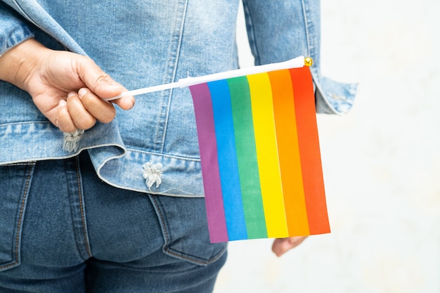 Azjatycka Dama Jest Ubranym Niebieską Dżinsową Kurtkę Lub Dżinsową Koszula I Trzyma Tęczowego Koloru Flaga, Symbol Dumy Lgbt Miesiąc.