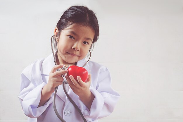 Azjatycka dziewczyna bawić się jako doktorska opieka zdrowy serce