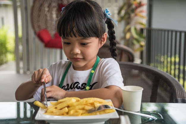 Azjatycka dziewczyna je frytki młode dziecko zabawa happy ziemniaczane fast food