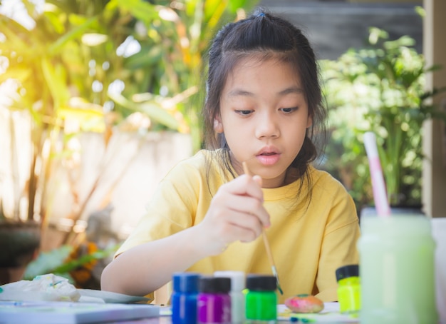 Azjatycka dziewczynka do kolorowania kamieni, twórcze dzieci z rockiem, kreatywne koncepcje dla dzieci