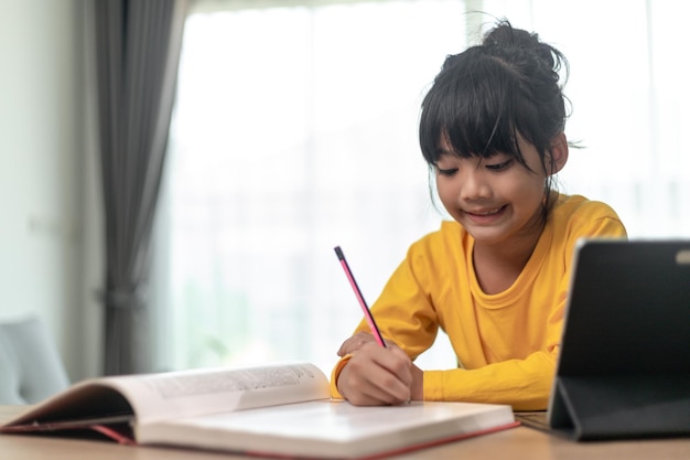Azjatycka dziewczynka uczęszcza na zajęcia on-line i cieszy się z koncepcji pandemii koronawirusa w szkole domowej kwarantanny