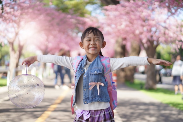 Azjatycka dziewczynka w ogrodzie pod drzewem kwiat sakura