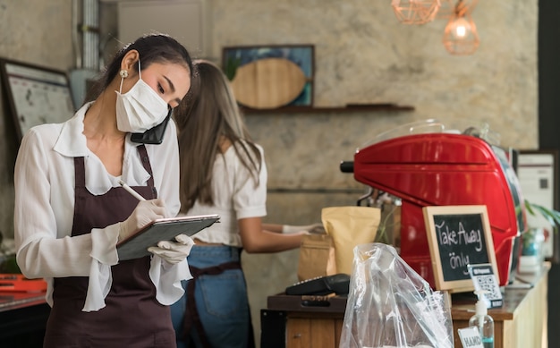 Zdjęcie azjatycka kelnerka przyjmuje zamówienia z telefonu komórkowego w celu zamówienia na wynos i odbioru przy krawężniku.