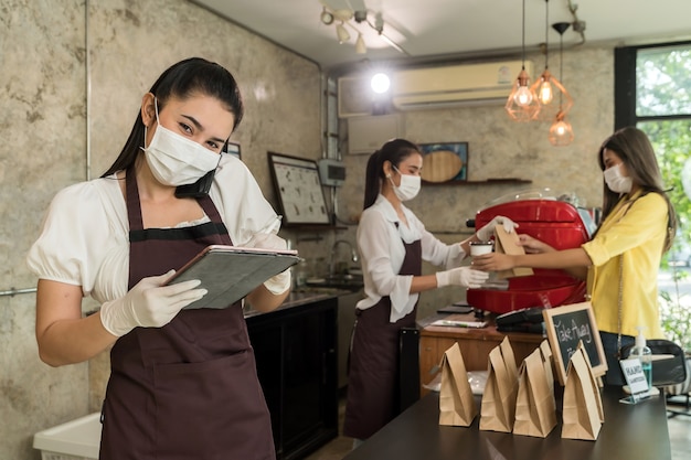 Zdjęcie azjatycka kelnerka przyjmuje zamówienia z telefonu komórkowego w celu zamówienia na wynos i odbioru przy krawężniku.