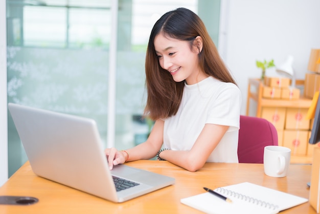 Azjatycka kobieta cieszy się podczas gdy używać laptopy i internet w biurze