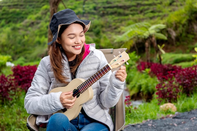 Azjatycka kobieta grająca na gitarze, ciesząca się aktywnością w obozie