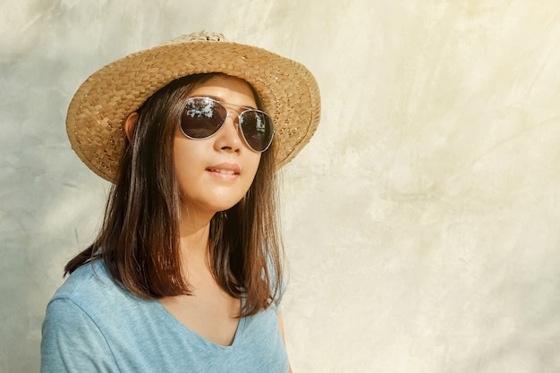 Azjatycka kobieta jest ubranym kapelusz, okulary przeciwsłoneczne i sunbathing.