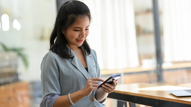Azjatycka kobieta korzystająca z nowoczesnego smartfona w aplikacji mobilnej sieci społecznościowej cafe