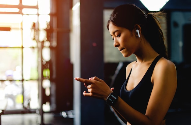 Azjatycka kobieta na siłowni i gra przez telefon podczas słuchania muzyki przed ćwiczeniami w centrum fitness