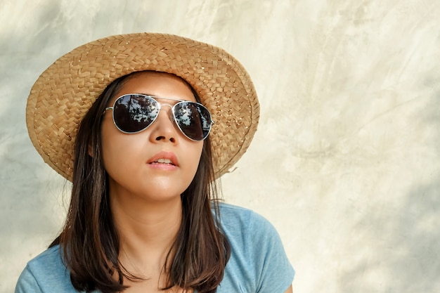 Azjatycka kobieta nosi kapelusz, okulary przeciwsłoneczne i opalanie.