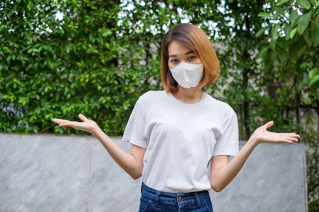 Azjatycka kobieta nosi maskę ochronną na twarz do prezentacji w domowym ogrodzie