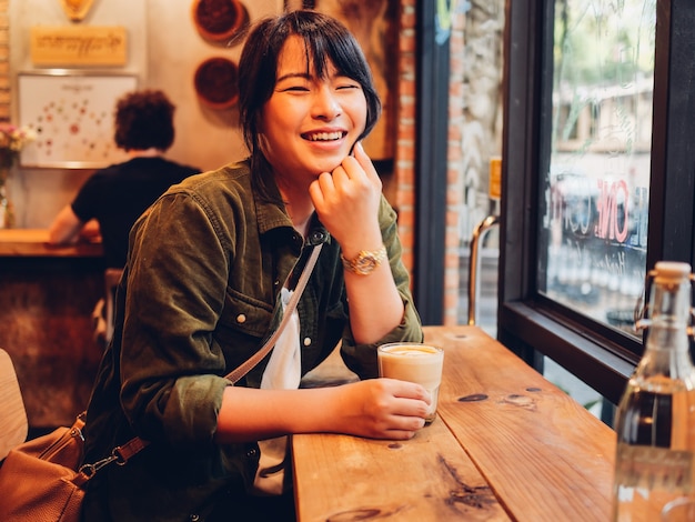 Azjatycka kobieta pije kawę w sklep z kawą kawiarni