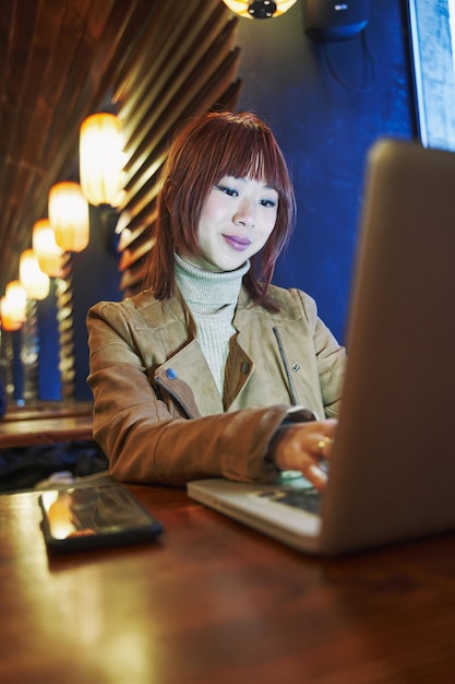 Azjatycka kobieta pracująca na komputerze w barze
