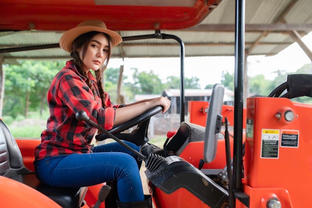 Azjatycka kobieta pracująca z traktorem na farmie krów Jedź traktorem, aby zaorać pola