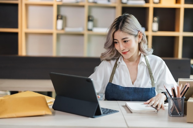 Azjatycka kobieta przedsiębiorca rozpoczynający działalność e-biznesową po sprawdzeniu zamówienia od dostawy zakupów online do sukcesu klienta na zakupach small businessxA