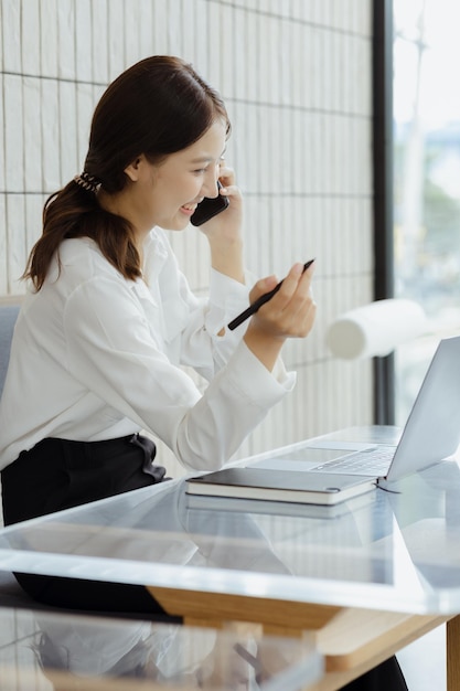 Azjatycka kobieta rozmawia przez telefon na kanapie w swoim gabinecie młoda bizneswoman założycielka firmy startowej prowadzącej biznes przez młode kierownictwo koncepcja biznesowa i prowadzona przez szefową