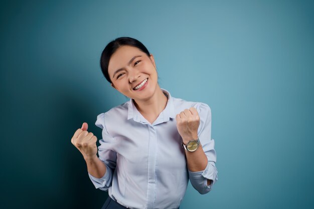 Azjatycka Kobieta Szczęśliwa Pewna Siebie Stojąca Pokazując Jej Pięść Zrobić Zwycięski Gest Odizolowany Na Niebiesko.