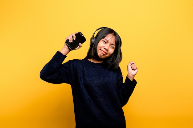 Azjatycka kobieta szczęśliwie korzystająca z telefonu i słuchająca muzyki Relaks przy muzyce W wygodny dzień Koncepcja tańca i relaksu słuchanie muzyki online